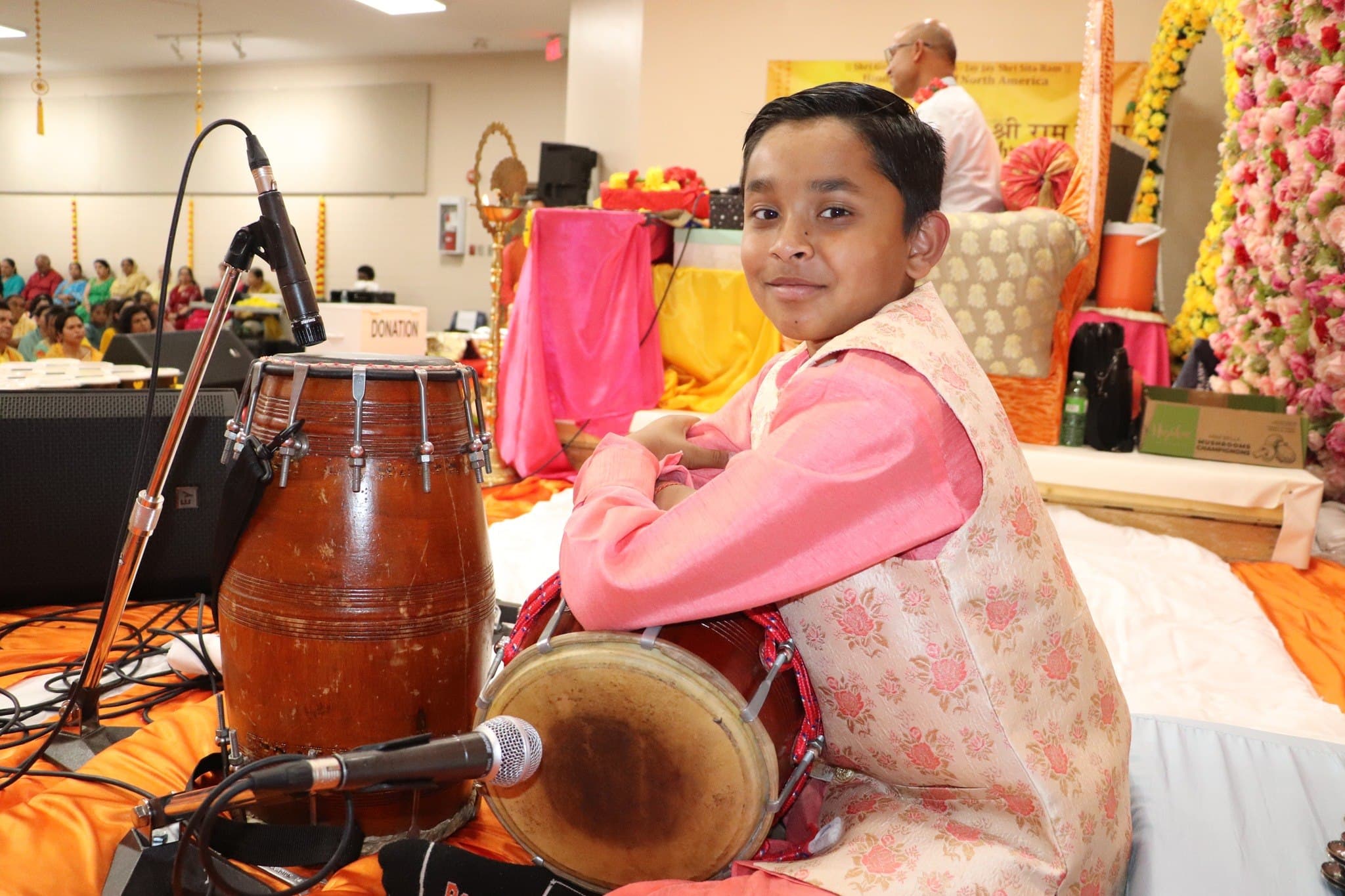 A young boy plays the dholak during the katha