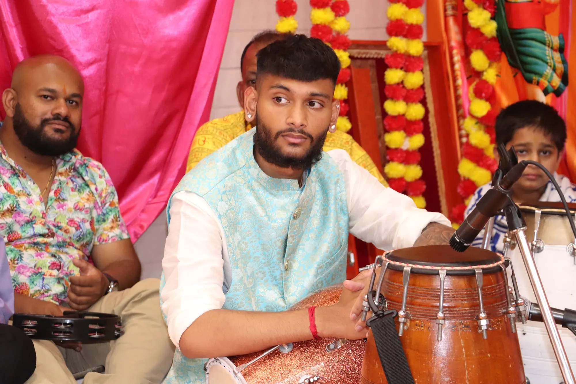 A musician playing the dholak during the kirtan