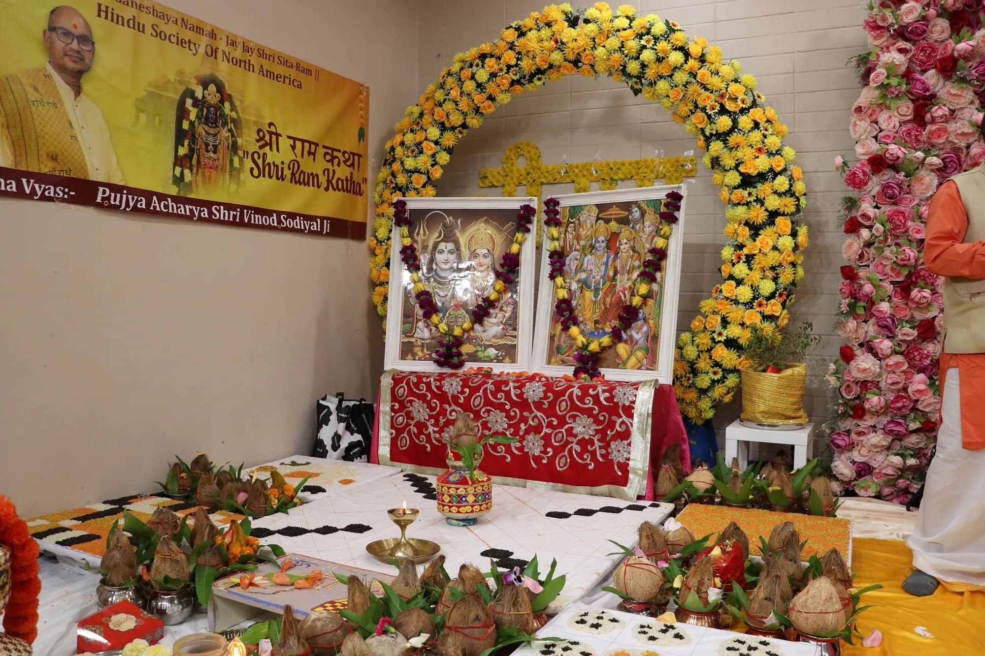 A flower-decked mandap with deities and offerings prepared for the katha