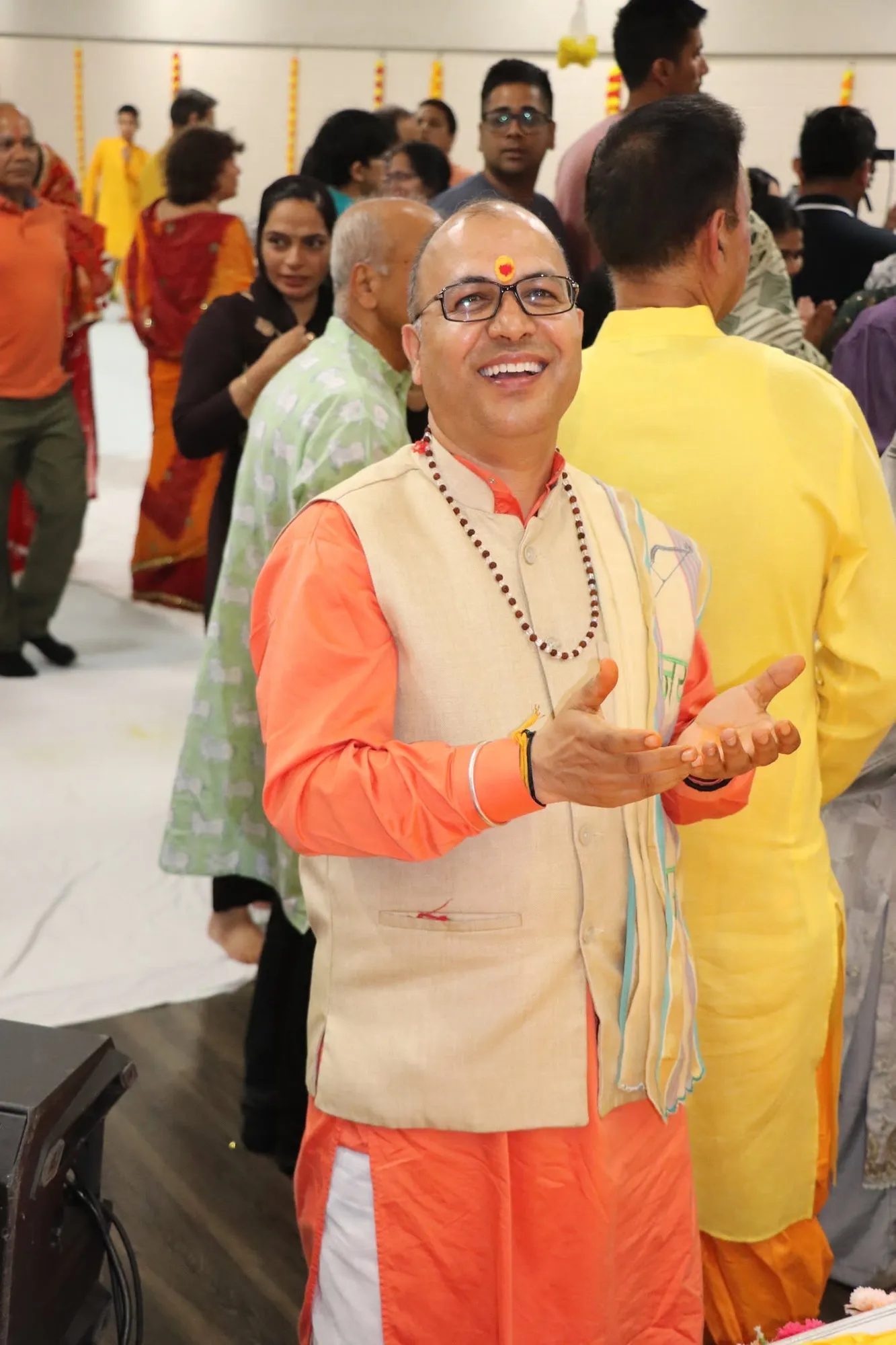 A devotee in saffron singing and clapping among the congregation