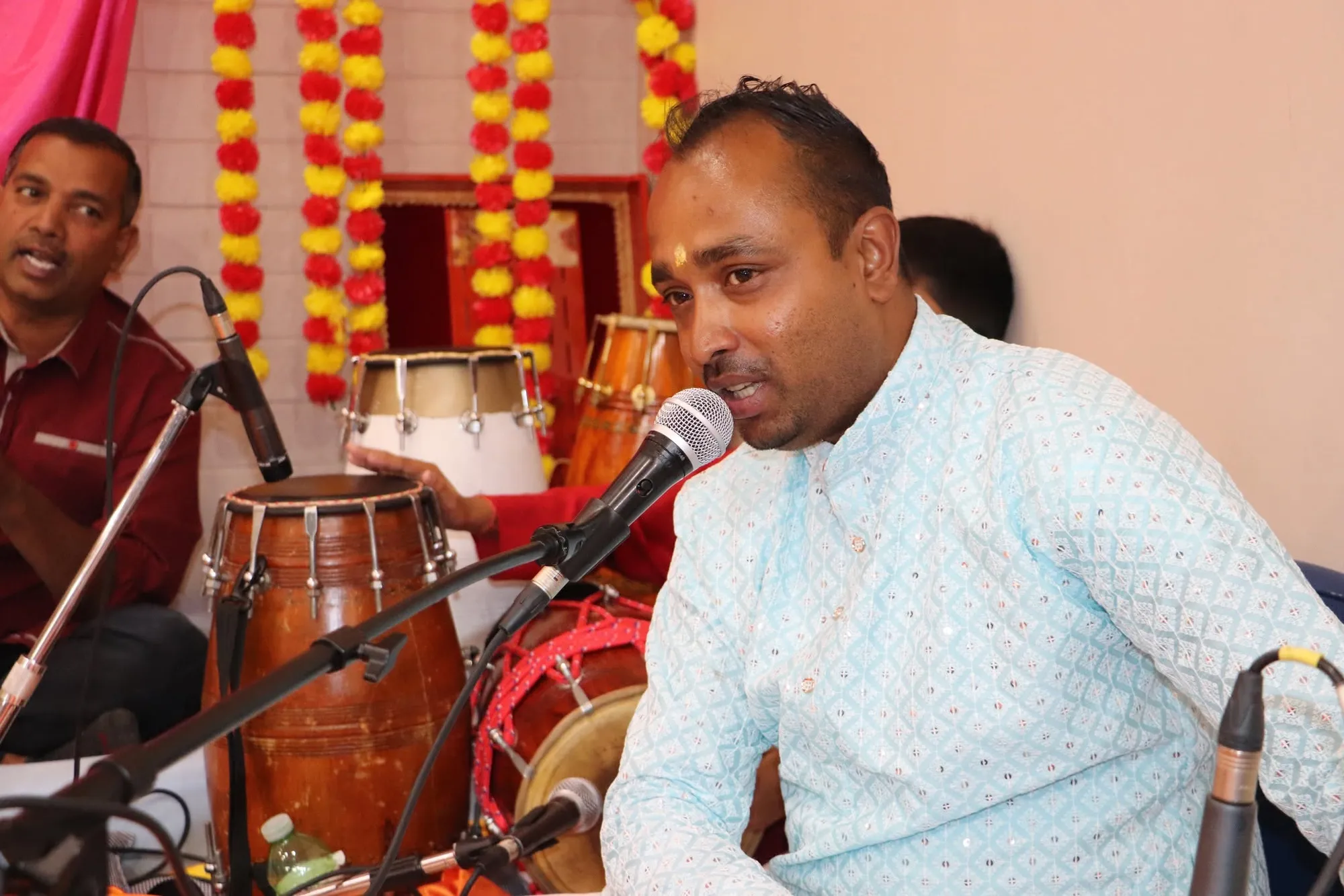A vocalist singing bhajans into the microphone