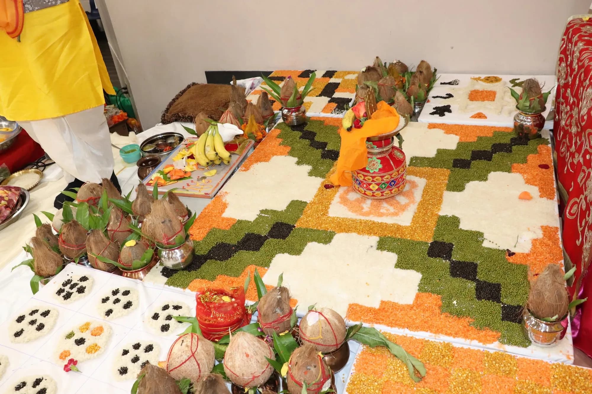 Grains, a kalash, and coconuts arranged in a colourful havan vedi