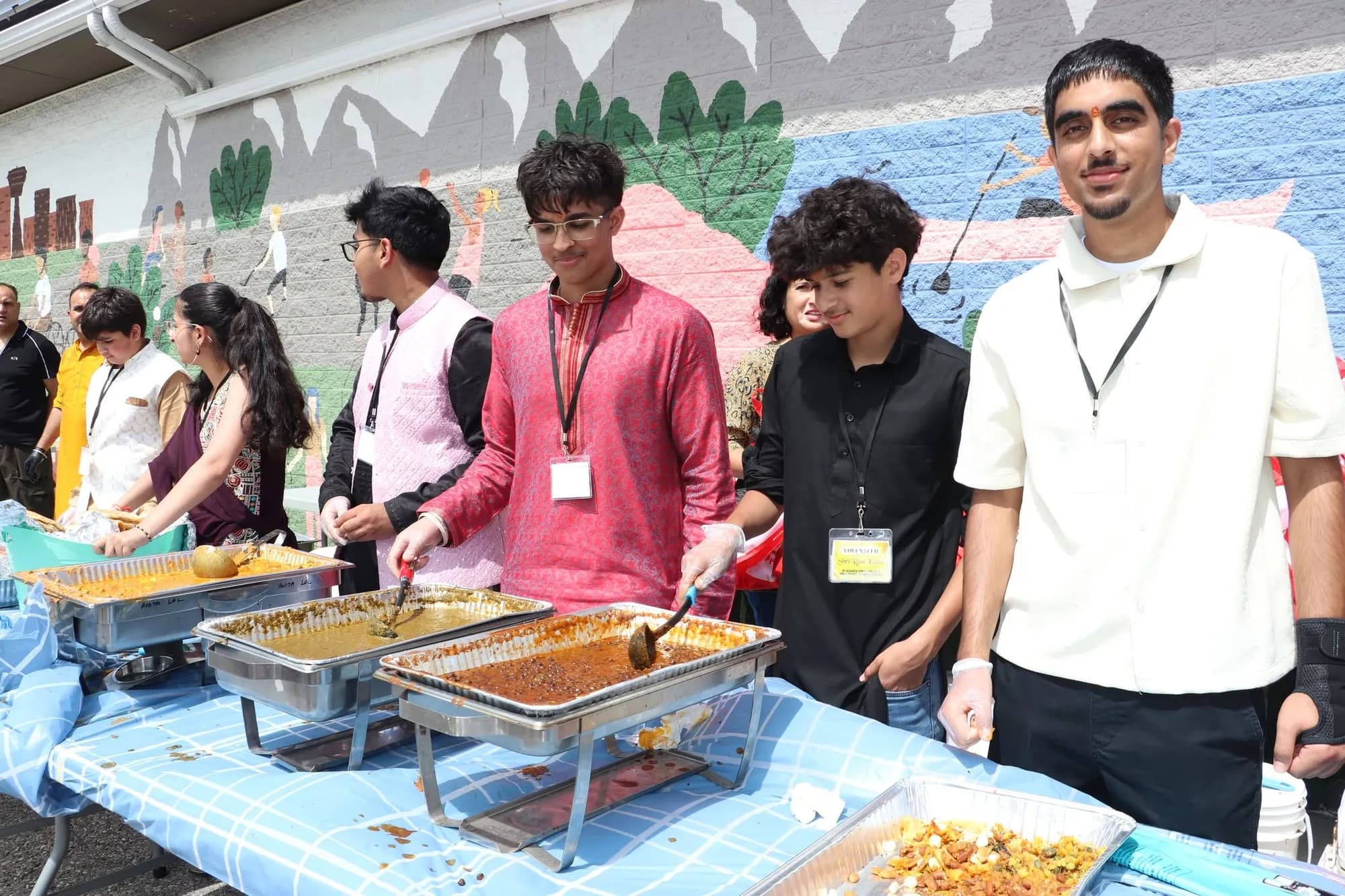 Young volunteers serving food from steam trays to the community