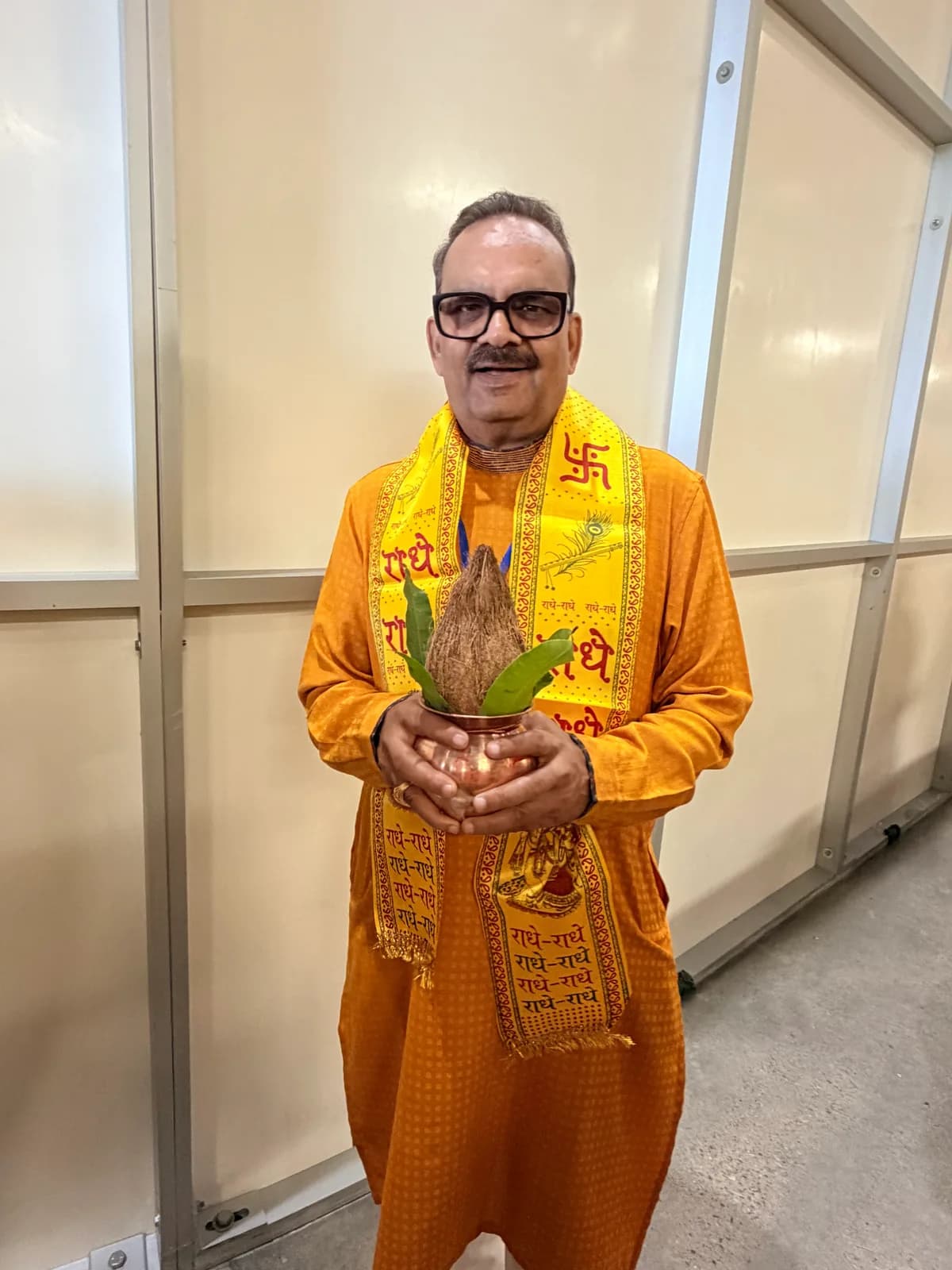 A devotee holds a kalash topped with a coconut and mango leaves