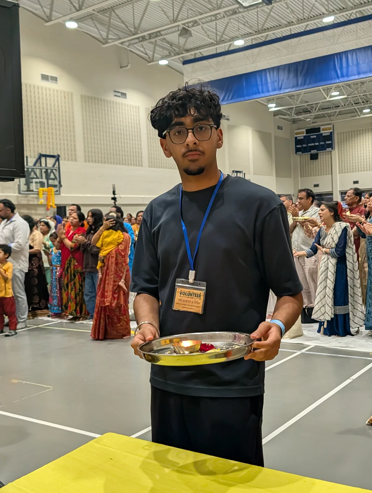 A volunteer carries the aarti thali through the hall