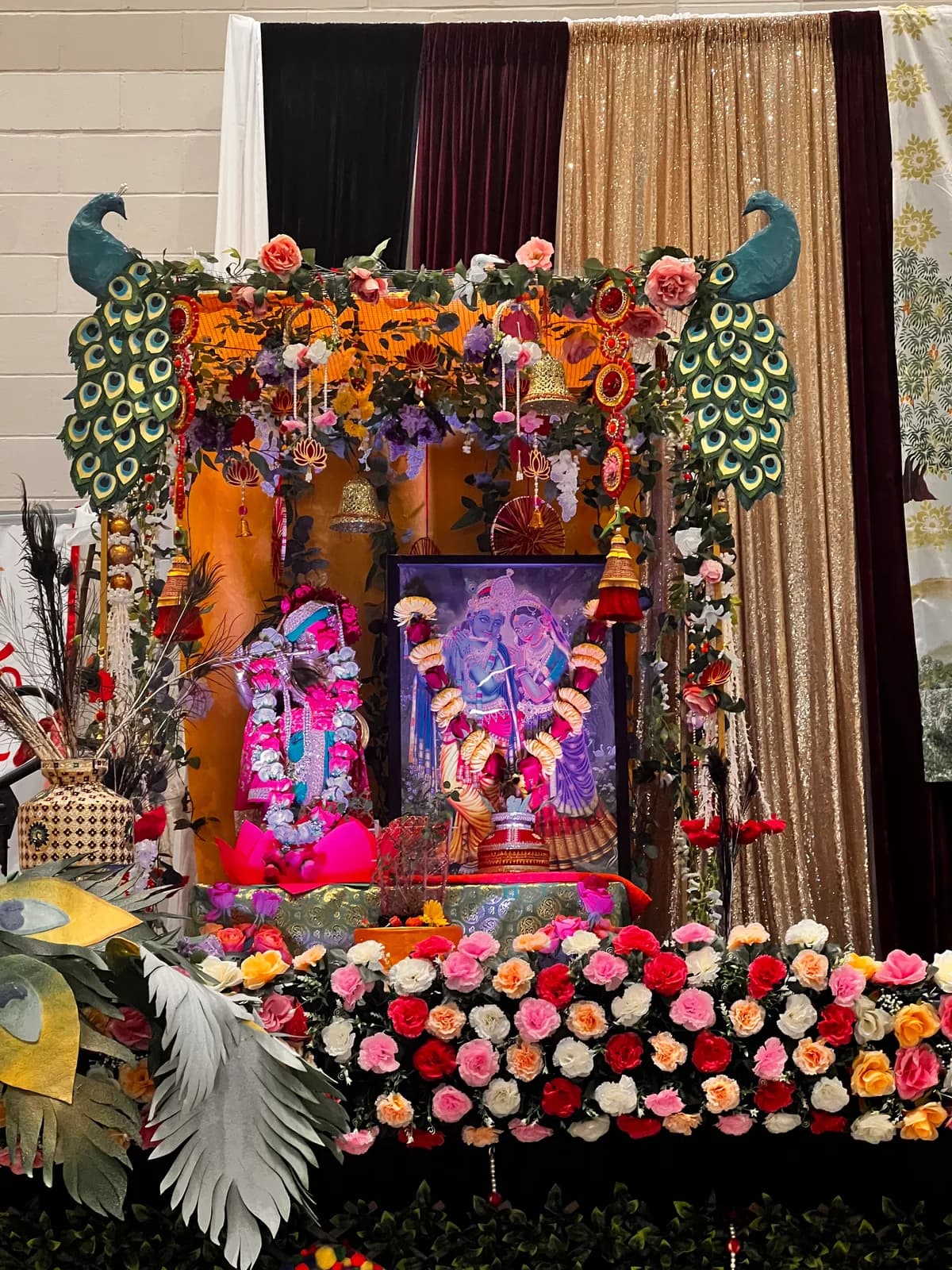 The flower-decked mandap and deities framed by peacocks on the opening evening